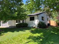 Charming painted brick home with lush landscaping and mature trees, offering shade and curb appeal at 2836 S Fenton St, Denver, CO 80227