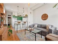 A cozy living room features an open kitchen with green cabinets, exposed brick, and hardwood floors at 474 N Inca St, Denver, CO 80204