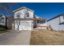 Two-story home with a two-car garage, a white porch, and a well-maintained front yard under a clear blue sky at 4931 S Danube St, Aurora, CO 80015