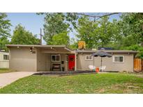 Charming home featuring a bright red front door, covered parking, and a cozy outdoor seating area at 1831 S Ivanhoe St, Denver, CO 80224