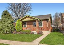 Charming brick home with well-maintained lawn, lush landscaping, and inviting front porch at 2050 S Lincoln St, Denver, CO 80210