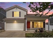 Inviting two-story home featuring a red front door, well-maintained lawn, and attached two-car garage at 19153 E 51St Ave, Denver, CO 80249