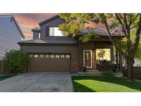 Charming two-story home featuring a well-maintained lawn, brick accents, and an attached two-car garage at 6898 W Rockland Pl, Littleton, CO 80128