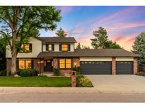 Charming two-story home with a three-car garage, landscaped yard, and classic colonial architecture against a beautiful sunset at 7308 S Steele Cir, Centennial, CO 80122