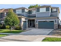 Inviting two-story home with a three-car garage, manicured lawn and a mix of stone and siding exterior at 12740 W 73Rd Pl, Arvada, CO 80005