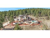 Stunning home with a stone exterior, multiple decks and outdoor entertainment areas, set amidst a lush, wooded landscape at 12555 Critchell Ln, Littleton, CO 80127