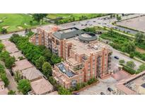 Brick condo building featuring balconies, patio, and roof deck is surrounded by trees and has a parking area at 2400 E Cherry Creek South Dr # 207, Denver, CO 80209