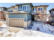 Two-story house with blue and beige siding, stone accents, and a snow-covered front yard at 9473 Kendrick Way, Arvada, CO 80007
