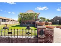 Charming brick home featuring a landscaped yard and unique architectural details on a sunny day at 5960 Glencoe St, Commerce City, CO 80022
