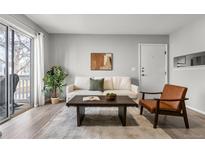 Bright living room featuring a white sofa, wood coffee table, and sliding glass doors to the outdoor area at 13333 E Asbury Dr # 104, Aurora, CO 80014