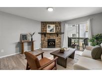 Cozy living room features a stone fireplace, comfortable seating and access to the outdoor balcony at 13333 E Asbury Dr # 104, Aurora, CO 80014