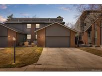 Two-story townhome showing painted siding, brick accents, and a concrete driveway leading to an attached garage at 2609 S Quebec St # 9, Denver, CO 80231