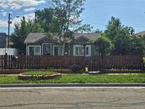 Charming cottage-style home with a well-maintained front yard, complemented by a quaint fence and lush greenery at 4368 Benton St, Denver, CO 80212