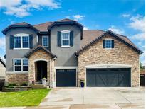Beautiful two-story home with stone and stucco exterior, three-car garage, and well-manicured lawn at 6738 Esmeralda Dr, Castle Rock, CO 80108