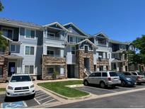 Three-story condo building features stone accents, blue siding, multiple balconies and convenient parking at 5255 Memphis St # 712, Denver, CO 80239