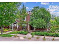 Charming two-story brick home featuring mature landscaping, a well-manicured lawn, and a welcoming front porch at 1160 S Sherman St, Denver, CO 80210