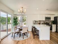Bright eat-in kitchen featuring white cabinets, an island with seating, and a dining table at 21472 E 46Th Ave, Denver, CO 80249