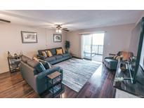 Inviting living room featuring a gray sofa set, ceiling fan, and sliding glass doors to the outside at 3460 S Poplar St # 204, Denver, CO 80224