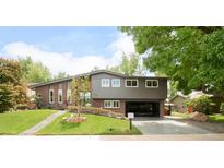 Charming home featuring brick and gray siding, lush landscaping, and a welcoming open carport at 10000 E Ohio Ave, Denver, CO 80247