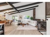Bright living room with beamed ceilings, stone fireplace, and sliding door access to the outside patio at 10000 E Ohio Ave, Denver, CO 80247