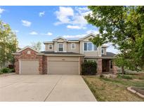 Stately two-story home featuring a three-car garage, a manicured lawn, and brick and siding details at 9453 Lark Sparrow Dr, Highlands Ranch, CO 80126
