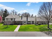 Charming two-story home featuring lush green lawn, beautiful landscape, and a brick pathway leading to the front door at 21 Huntwick Ln, Cherry Hills Village, CO 80113