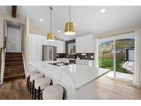 Bright, remodeled kitchen with island seating, stainless appliances, and sliding door access to backyard at 18866 W 59Th Pl, Golden, CO 80403