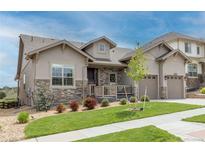 Charming home with stone accents, a covered porch, landscaped yard, and a two-car garage in a suburban neighborhood at 11890 Discovery Cir, Parker, CO 80138