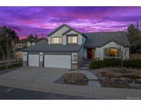 Charming two-story home with a three-car garage, manicured landscaping, and a cozy front porch at twilight at 4530 Ridgewood Ct, Castle Rock, CO 80109