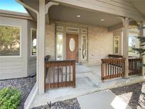 Covered front porch with brick facade and detailed wood features at 7292 Firethorn, Littleton, CO 80125
