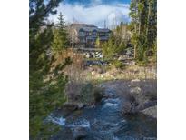 Beautiful mountain home with creek in foreground, trees, and blue sky at 100 River Park Dr # A, Breckenridge, CO 80424