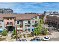 Apartment building with balconies, parking, and sidewalks on a sunny day at 3195 Blake St # 106, Denver, CO 80205