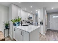 Well-lit kitchen with white cabinets, stainless appliances, and an island with a black faucet at 1811 S Quebec Way # 103, Denver, CO 80231