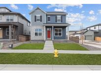Charming two-story home with a red door, landscaped yard, and concrete walkway, with a fire hydrant in the front yard at 21202 E 63Rd Dr, Aurora, CO 80019