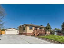 Charming single-story brick home with a well-maintained front yard, wooden porch, and detached garage with a driveway at 3871 Moore St, Wheat Ridge, CO 80033