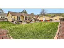 Expansive backyard featuring a lush lawn, covered patio, and charming landscaping at 15325 W 32Nd Ave, Golden, CO 80401