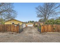 Quaint yellow home behind a gated entrance with a detached garage and basketball hoop at 15325 W 32Nd Ave, Golden, CO 80401