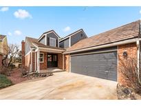 Brick front exterior with gray garage doors and landscaping at 7079 S Locust Pl, Centennial, CO 80112
