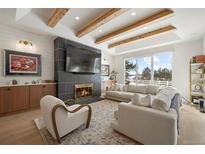 Bright living room featuring a fireplace, wood beams, large windows, and modern furnishings at 7079 S Locust Pl, Centennial, CO 80112
