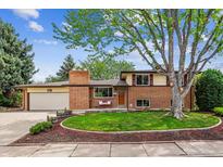 Charming brick home featuring a lush lawn, mature tree, and a cozy front porch seating area at 2990 S Jay St, Denver, CO 80227