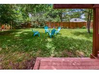 Lush backyard featuring a grassy lawn, wooden fence, and four Adirondack chairs at 3071 S Jasmine St, Denver, CO 80222