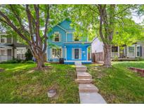 Charming two-story blue home with a welcoming front porch and beautiful, mature trees at 2645 Osceola St, Denver, CO 80212