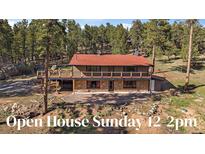 Charming home with a stone facade, wooden deck, and red roof nestled among mature trees at 34 Normandy Rd, Evergreen, CO 80439