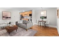 Bright living room featuring hardwood floors, modern furnishings, and an open layout into the kitchen and dining area at 558 N Washington St # 305, Denver, CO 80203
