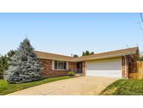Brick home featuring an attached two-car garage, a well-manicured lawn, and mature trees at 6212 S Ash W Cir, Centennial, CO 80121