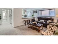 Inviting living room with leather sofa, ottoman, and bar seating overlooking the kitchen at 352 S Lafayette St # 204, Denver, CO 80209