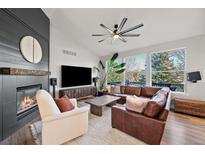 Cozy living room featuring a fireplace, leather sofa, and views of the outdoors at 1053 Snow Lily Ct, Castle Pines, CO 80108