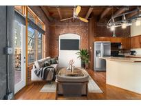 Bright living room features exposed brick walls, hardwood floors, and large windows at 2960 Inca St # 308, Denver, CO 80202