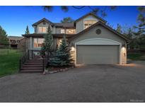 Charming home with a two-car garage, landscaped front yard, and inviting front porch area at 31402 N Bermuda Dunes Dr, Evergreen, CO 80439