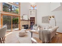 Bright living room with stone fireplace, hardwood floors, and large windows offering natural light at 31402 N Bermuda Dunes Dr, Evergreen, CO 80439